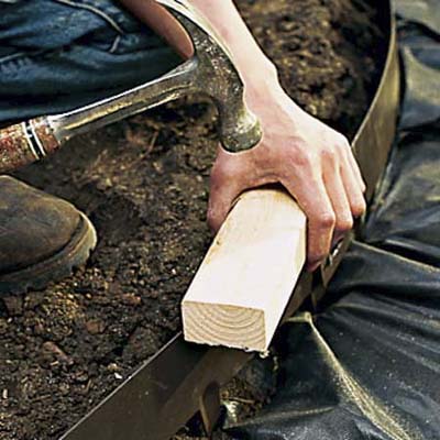 Tapping down the edging, using a hammer.
