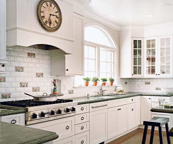 A kitchen with white painted glass front cabinets, beadboard accents and white light fixture  give a vintage look