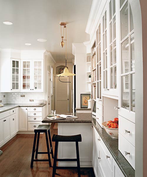 A kitchen with white painted glass front cabinets, beadboard accents and white light fixture  give a vintage look