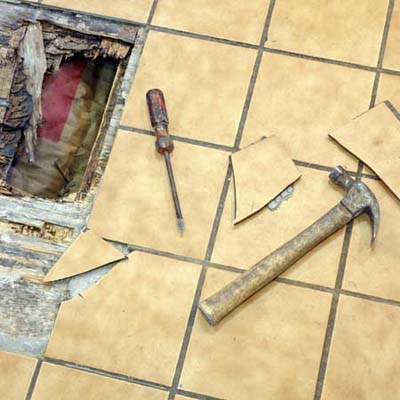 a hole in the floor with floor tiles in a state of repair
