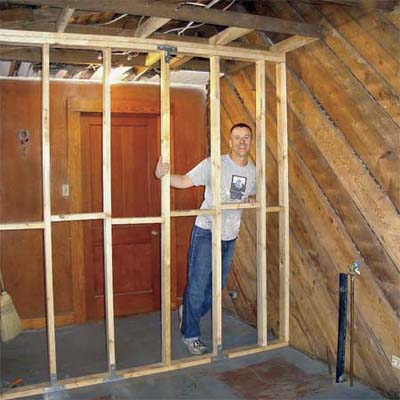 bungalow homeowner standing behind bare studs in unfinished room