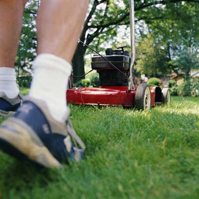 view of man's sneakers as he mows the lawn