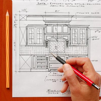 hand holding pen over kitchen cabinet plans