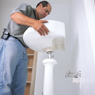 man installing pedestal sink in bathroom