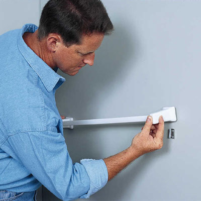 man anchoring towel bar in bathroom
