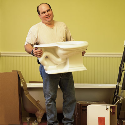 man holding new toilet before installing it in bathroom