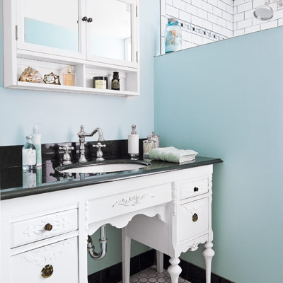 vintage bathroom with blue walls and vintage desk vanity with sink