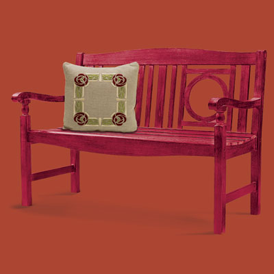 a bench made in the Arts & Crafts style with a linen pillow embroidered with a rose wreath design
