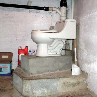 a toilet in a basement mounted about two feet off the floor