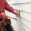 man prying off damaged clapboard