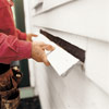 man removing damaged clapboard from house exterior