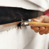 man removing bottom nails of clapboard siding