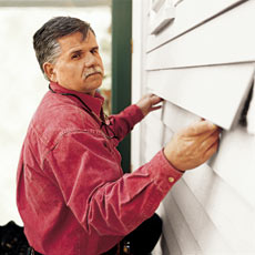 man replacing damaged clapboard with new one