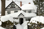 house and trees burdened by extreme snow fall