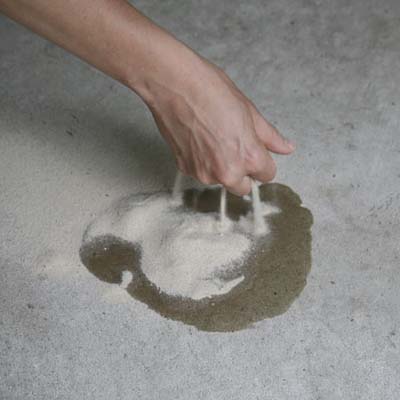 hand covering oil leak with sand