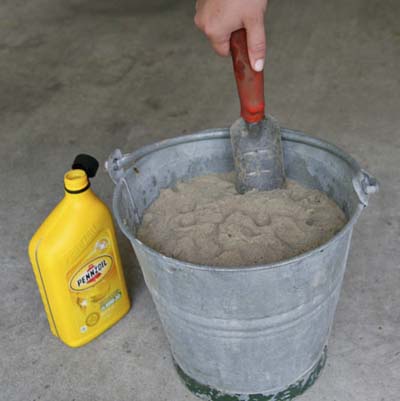 hand dipping garden tool in bucket of sand