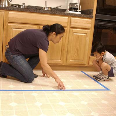 child home safety, child-proofing, and accidental injury prevention in the kitchen: woman mapping out kitchen stove area with child
