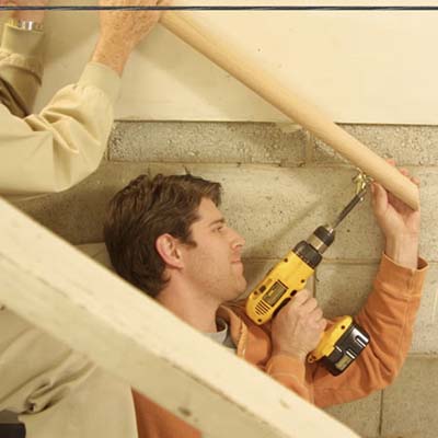 child home safety, child-proofing, and accidental injury prevention in stairways and staircases: man using drill to secure staircase rail