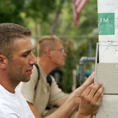 taking measurements before fastening the first course of siding