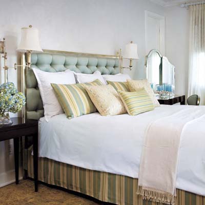 bedroom features cushioned headboard, patterned pillows and vanity mirror