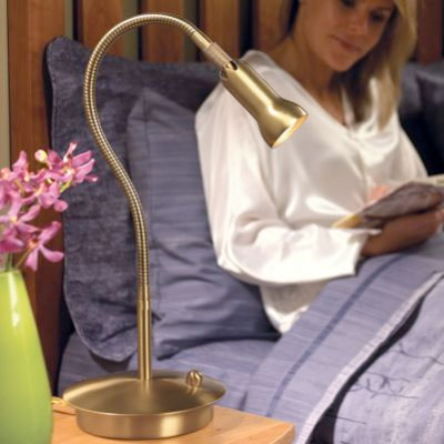 woman reads next to levenger reading lamp on bedside table