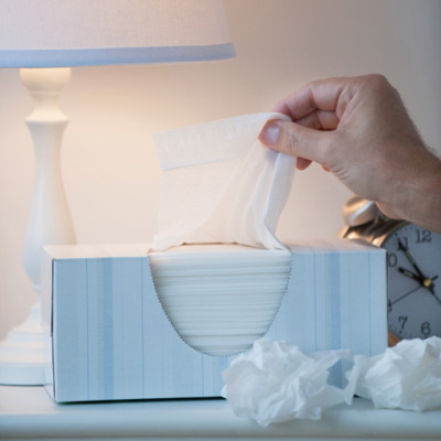 man reaching for tissue on bedside table because of allergies