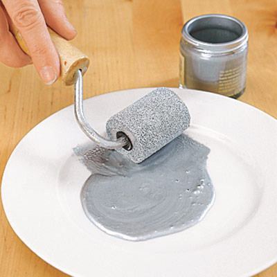 paint roller and silver paint on white plate