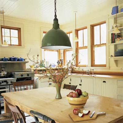 large green pendant light hanging above a rustic kitchen table
