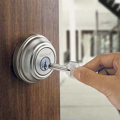 hand pushing a key into a door lock