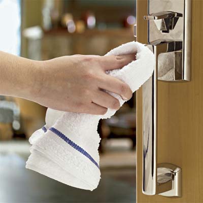 hand wiping down the handle of an entry set with a towel