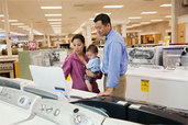 two adults and a baby shopping in an appliance showroom