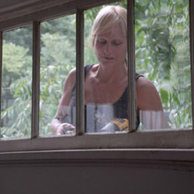 woman seen through window stringing siding