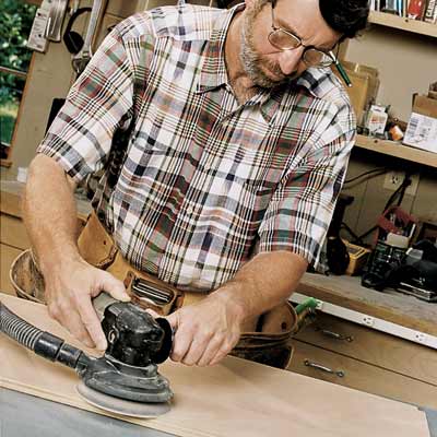 man sanding flat surface with random orbit sander