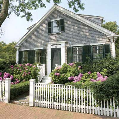 beautiful white picket fence before a house and flower garden