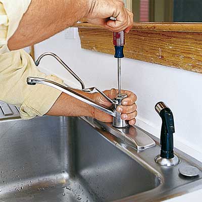 hands repairing a kitchen faucet with a screwdriver