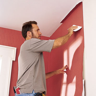 man applies wallpaper to a wall