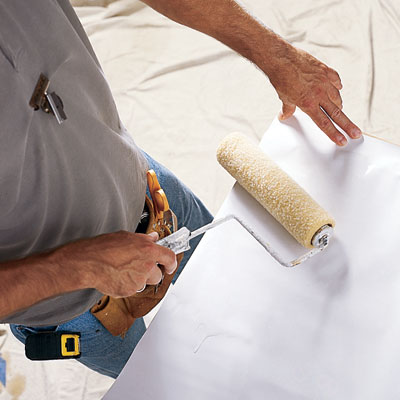 applying wallpaper paste to the backside of a sheet of wallpaper