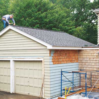 man installing shingles on gabled roof