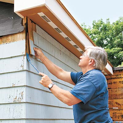 man replacing wood siding on house