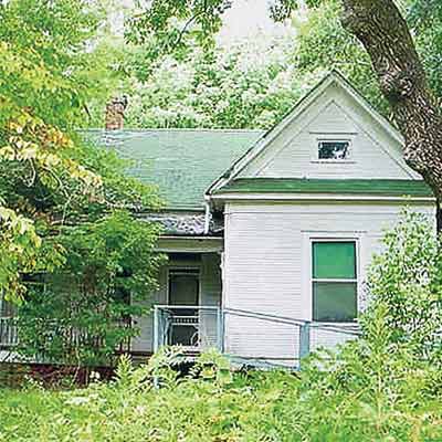 folk victorian house hidden with overgrown brush
