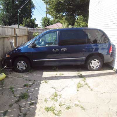 mini van parked between house and fence with no room to either end