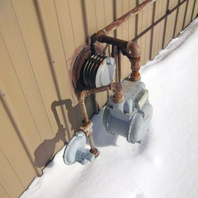 Gas wall mounted space heater and gas meter on side of house