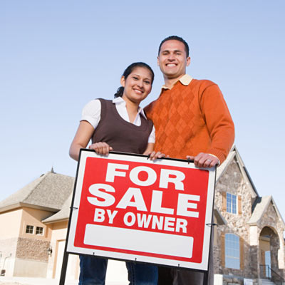 couple standing in front of for sale by owner sign