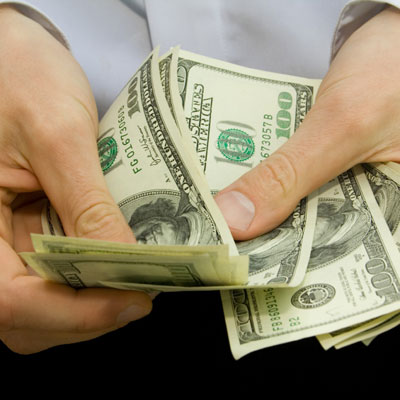 man's hands holding one hundred dollar bills