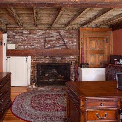 exposed-beam ceilings and brick fireplace surround in the study of the bedford house before this old house remodel