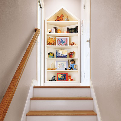 peaked bookshelf creating a  focal point at the top of an attic stairway in this refinished attic 
