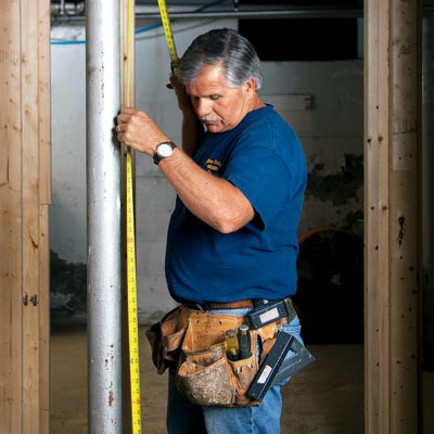 Tom Silva measures a lally-column with his custom tool belt on