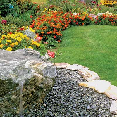 a flowery, colorful garden in late summer with stone edging
