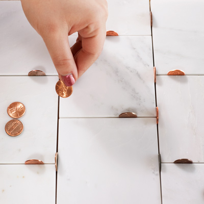 pennies on end between tiles 