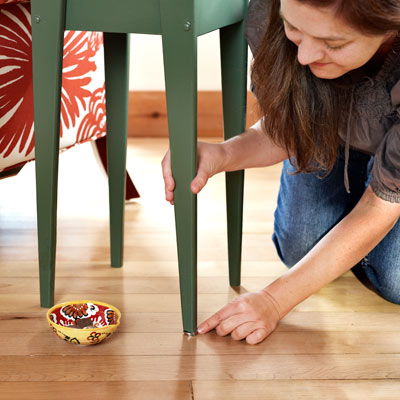 woman putting a penny under a shaky table leg